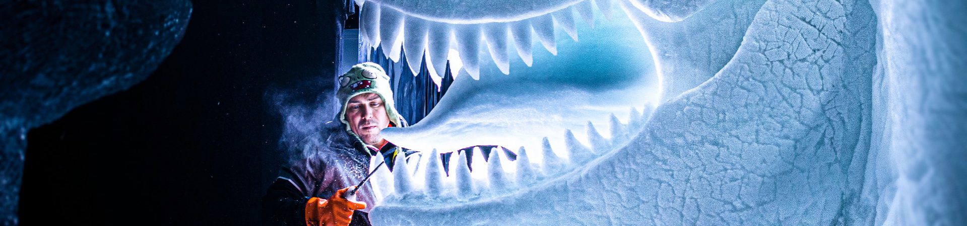 Een beeldhouwder die gelikt wordt door een gigantische dinosaurus van ijs